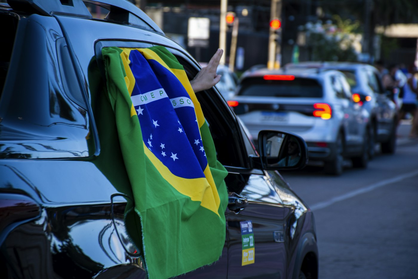 Bandeira do Brasil na janela de um carro durante uma carreata